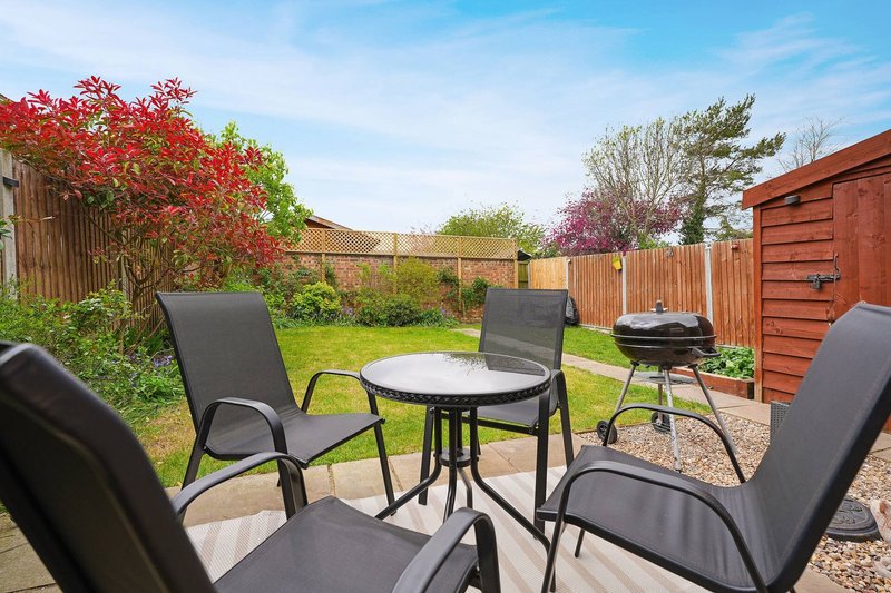Backyard garden with patio seating area, round table, black chairs and shed