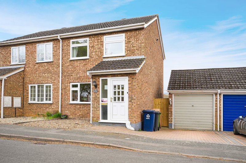 Brick semi-detached house with white door, driveway, garage and blue bins