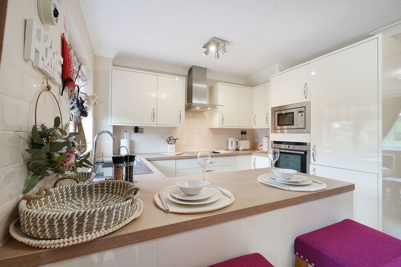 Modern white kitchen with wooden countertop, island seating, and holiday decorations