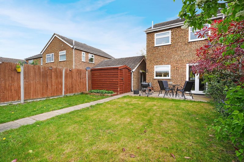 Suburban garden with lawn, wooden fence, brick houses and patio seating area