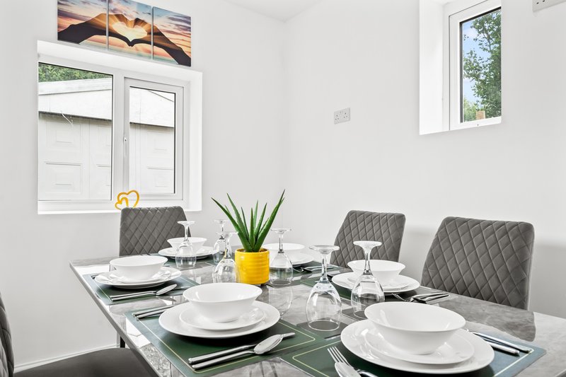 Modern dining room with glass table, grey upholstered chairs, and place settings