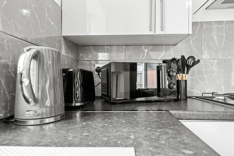 Modern kitchen countertop with stainless steel kettle, microwave, and kitchen utensils