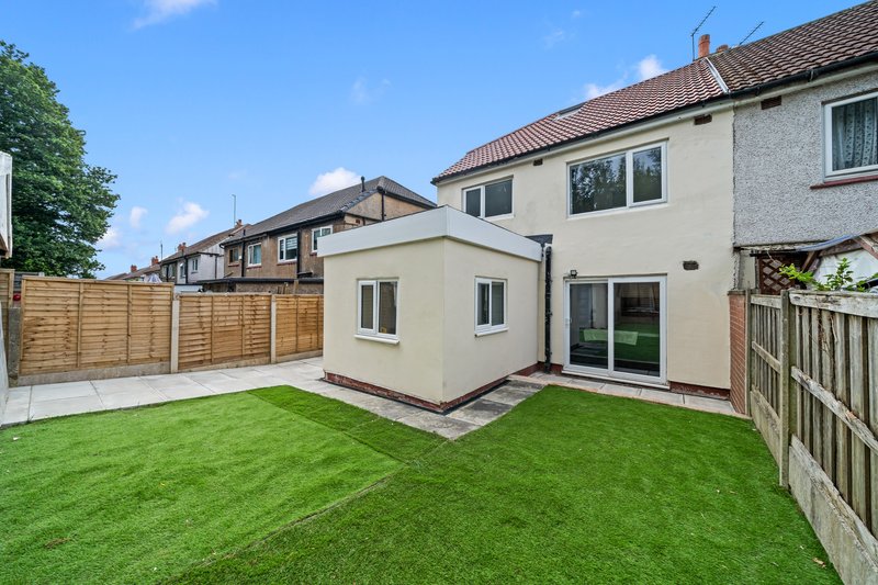 Modern single-story extension with patio, manicured lawn and wooden fencing