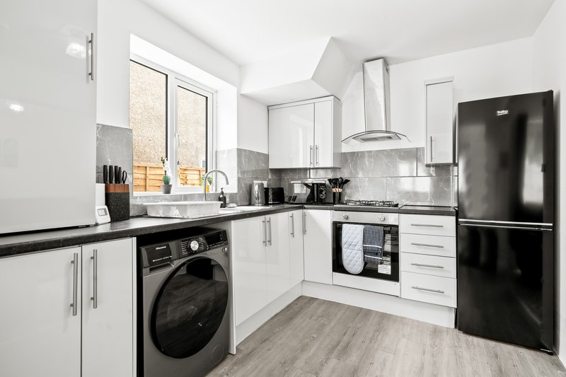 Modern kitchen with white cabinetry, black appliances, gas hob and washing machine