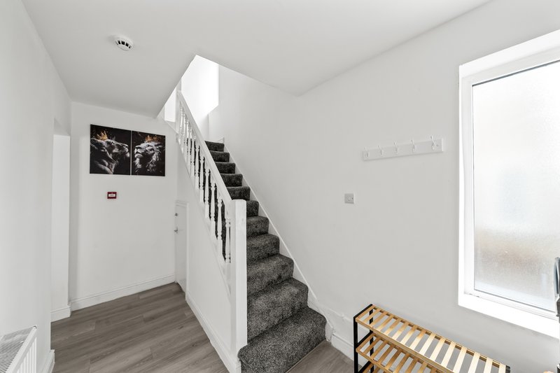 Modern hallway with staircase, white walls, gray carpet stairs and wooden flooring