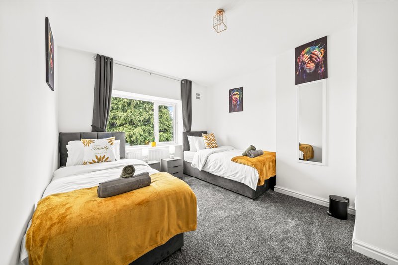 Bright twin bedroom with yellow blankets, grey carpet, and framed wall art