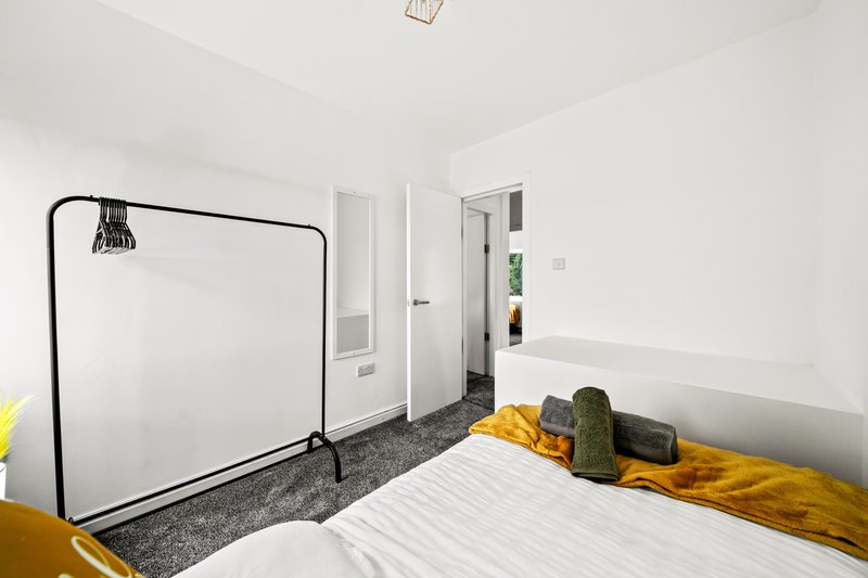 Bright bedroom with single bed, yellow bedding, whiteboard on stand, and white walls