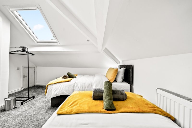 Bright attic bedroom with skylight, double bed, yellow bedding, and minimalist decor