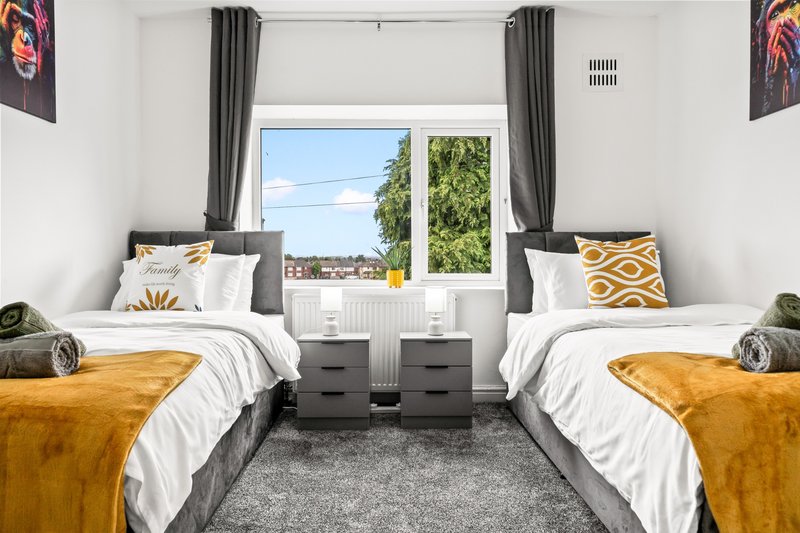 Twin bedroom with two single beds, grey carpet, large window with countryside view and curtains