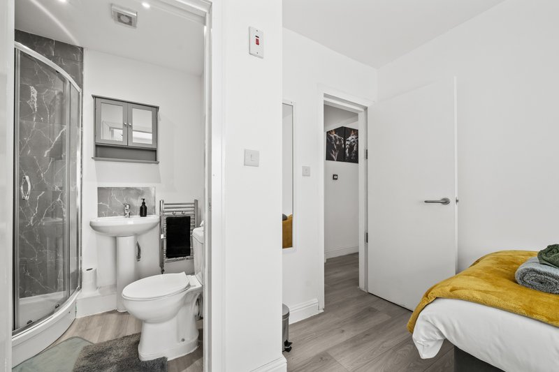 Bedroom with double bed and ensuite bathroom featuring shower, toilet and sink