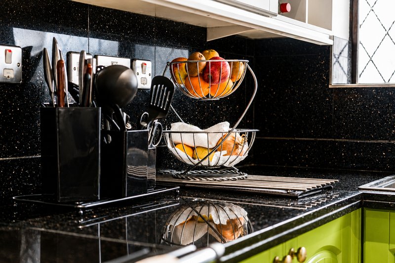 Modern kitchen with black speckled countertop, lime-green cabinetry, and fruit baskets