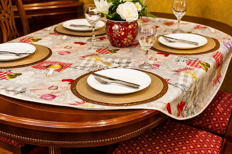 Formal dining table set with floral tablecloth, place settings, and white flower centerpiece