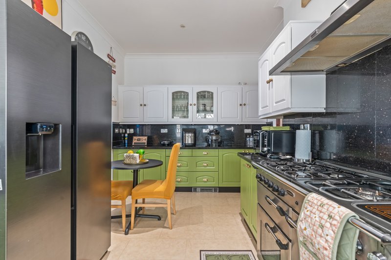 Modern kitchen with lime green cabinetry, black countertops, stainless steel appliances, and dining area
