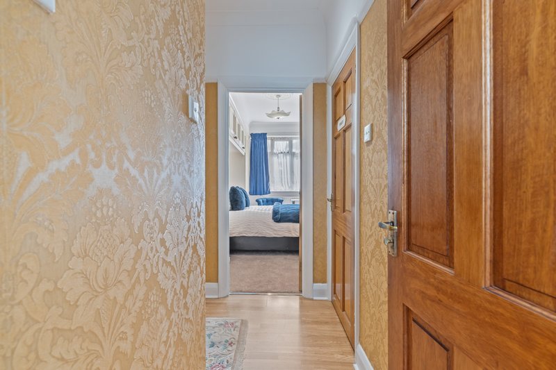 Hallway with wooden doors and patterned wallpaper, view through to bedroom