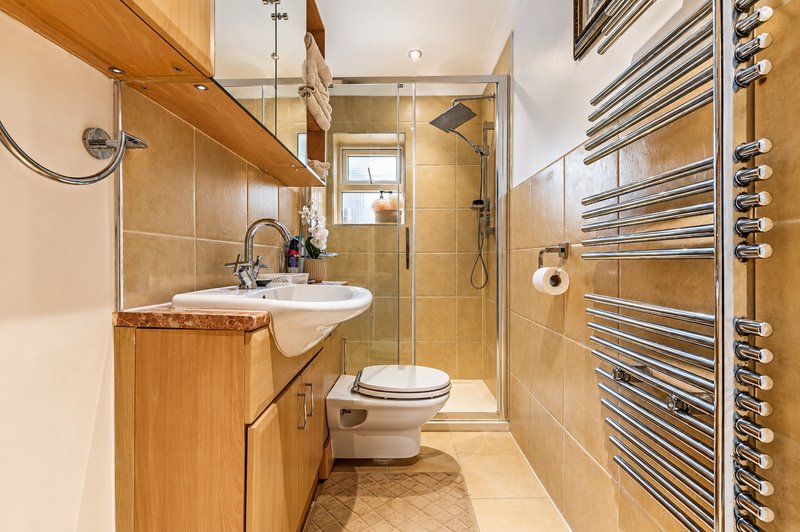 Modern bathroom with wooden vanity, walk-in shower, heated towel rack and toilet