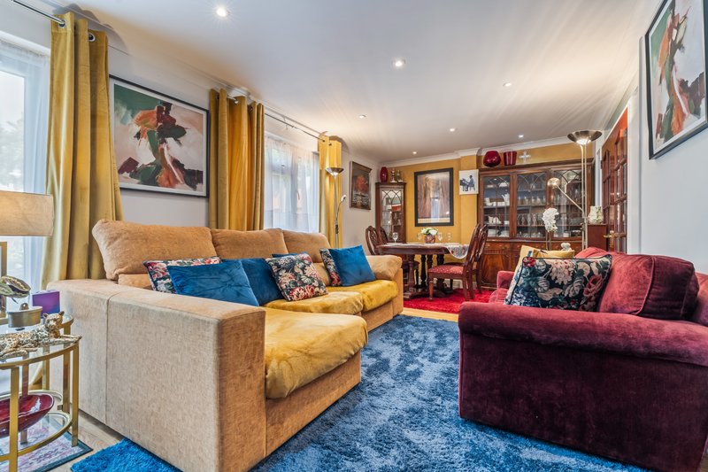 Spacious living room with mustard and burgundy sofas, blue rug, gold curtains and artwork
