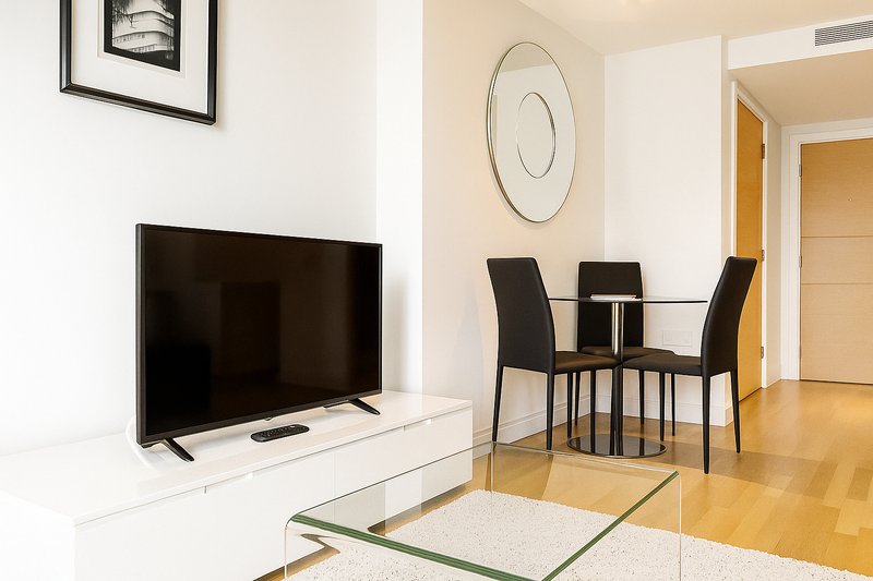 Modern living room with TV, dining table, chairs and wooden flooring