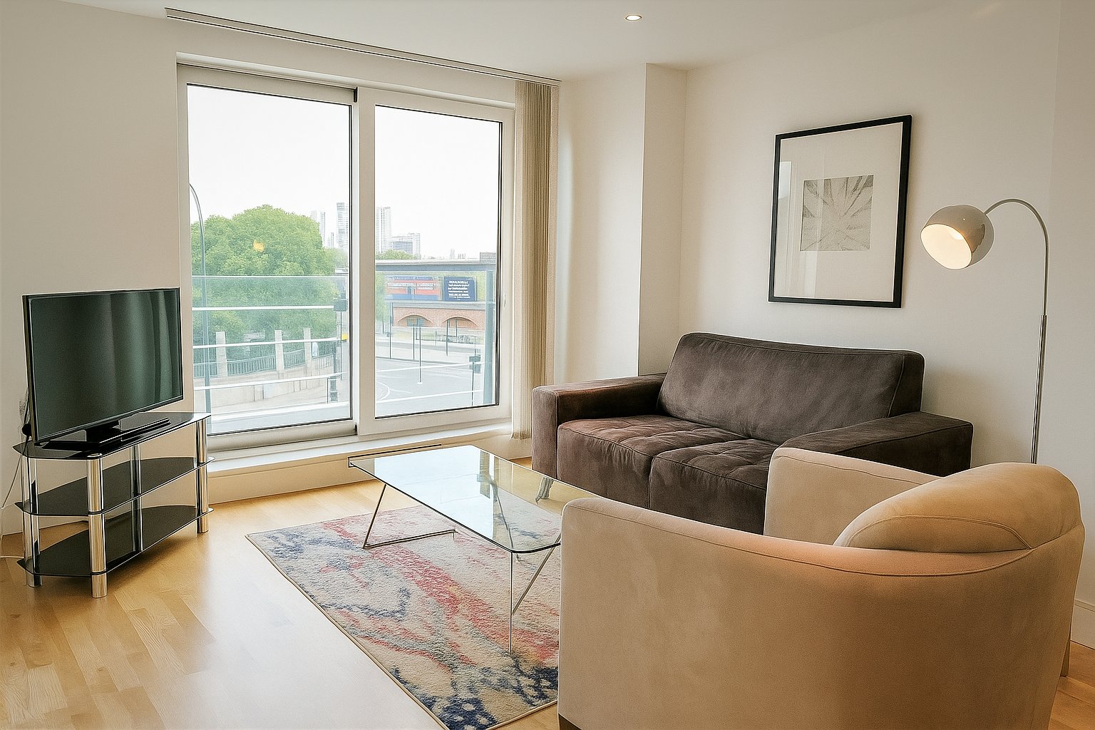 Modern living room with sofa, armchair, TV, glass coffee table and balcony doors