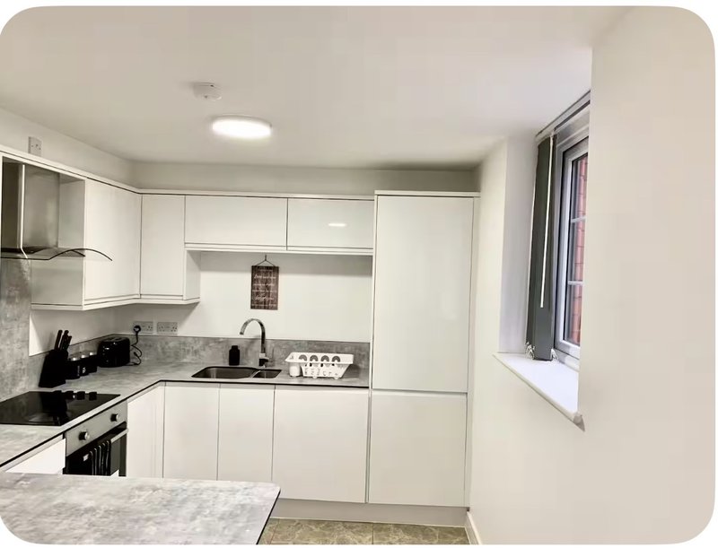 Modern white kitchen with granite countertop, built-in appliances and window