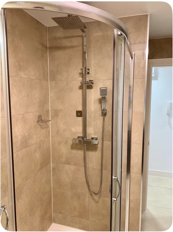 Modern bathroom with enclosed shower cubicle, rainfall showerhead, and beige tile walls