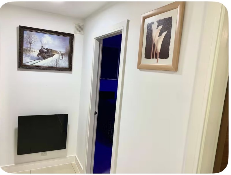 Hallway with framed artwork, flat-screen TV, and blue closet door