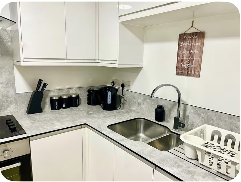 Modern white kitchen with gray countertop, stainless steel sink, and basic appliances