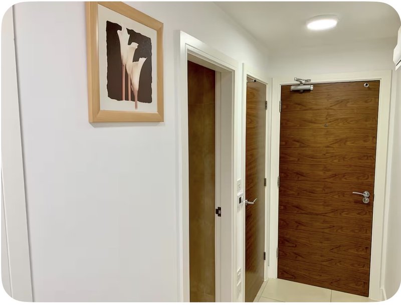 Hallway with white walls, wooden doors, framed wall art and ceiling light