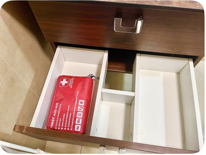 Bathroom vanity drawer open showing first aid kit and storage compartments