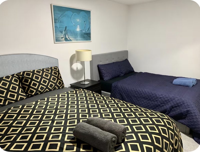 Bedroom with two twin beds, patterned bedding, lamp, and framed artwork on wall