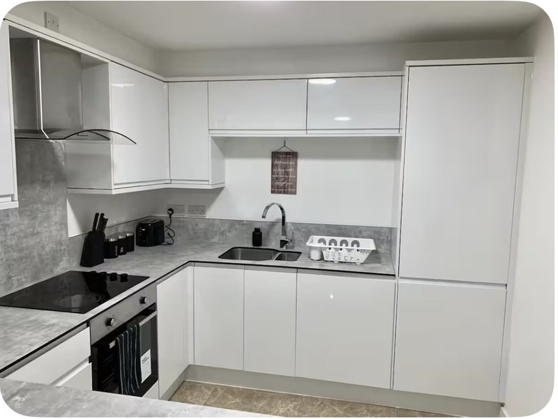 Modern white kitchen with black countertop, integrated appliances, and sink
