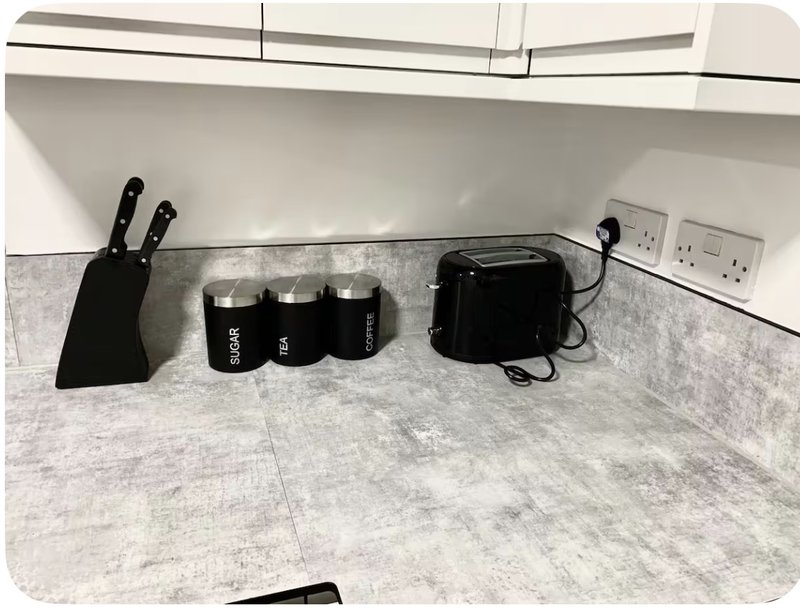 Modern kitchen countertop with knife block, black canisters, and appliance