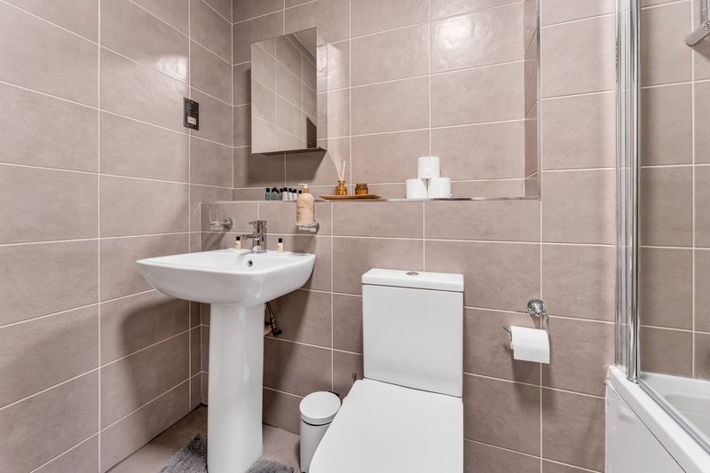 Modern bathroom with pedestal sink, toilet, mirror and shower enclosure