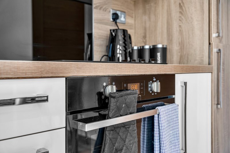 Modern kitchen with white cabinetry, wooden countertop, and built-in appliances