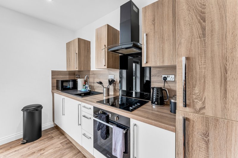 Modern kitchen with white and wood cabinetry, black appliances, and wooden countertop