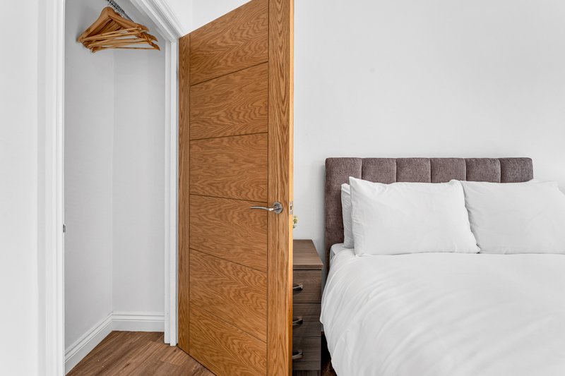 Bedroom with double bed, wooden wardrobe, white pillows and wooden floor