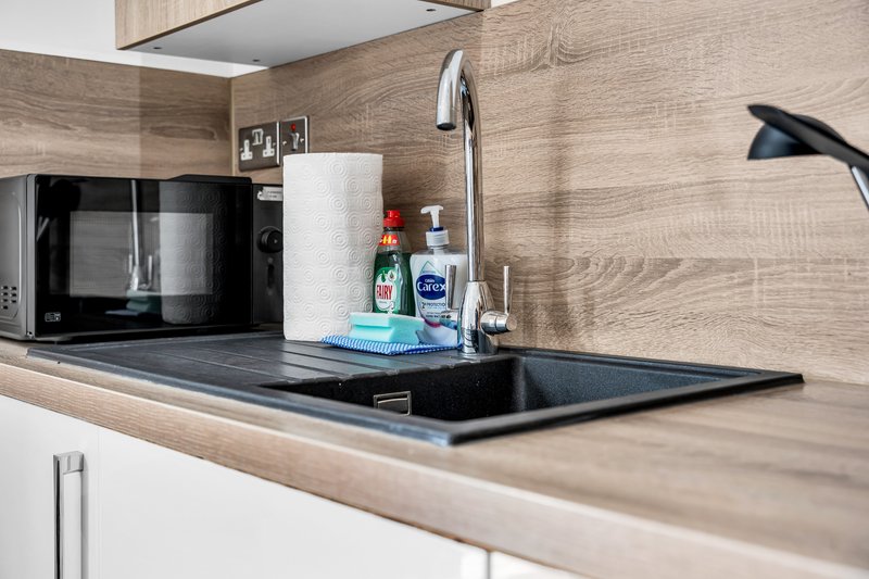 Modern kitchen countertop with microwave, sink, faucet and toiletries