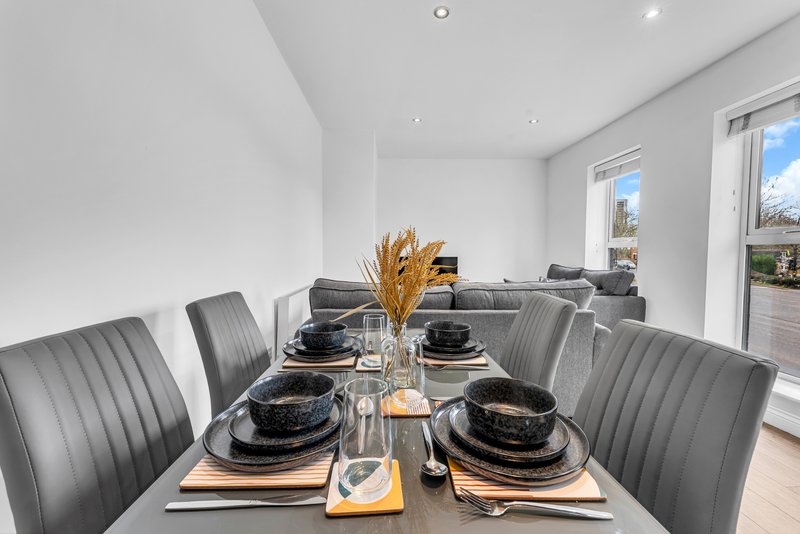 Modern dining room with grey upholstered chairs, black table, and place settings