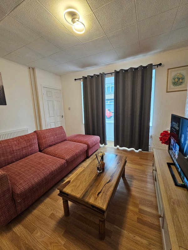 Living room with red plaid sofa, wooden coffee table, dark curtains, and ceiling light