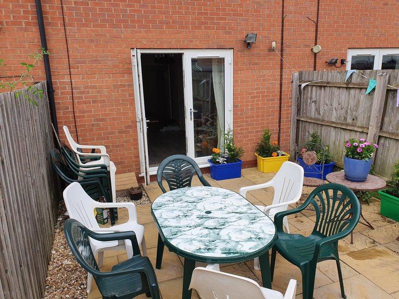 Brick patio area with outdoor dining table, mixed seating chairs, potted plants, and French doors