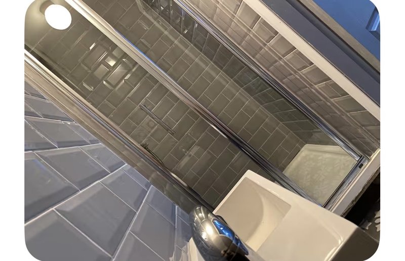 Modern bathroom with dark tile walls, white sink basin, and chrome fixtures