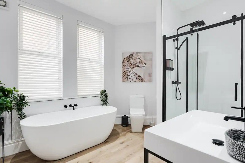 Modern bathroom with freestanding white bathtub, walk-in shower, and wooden flooring