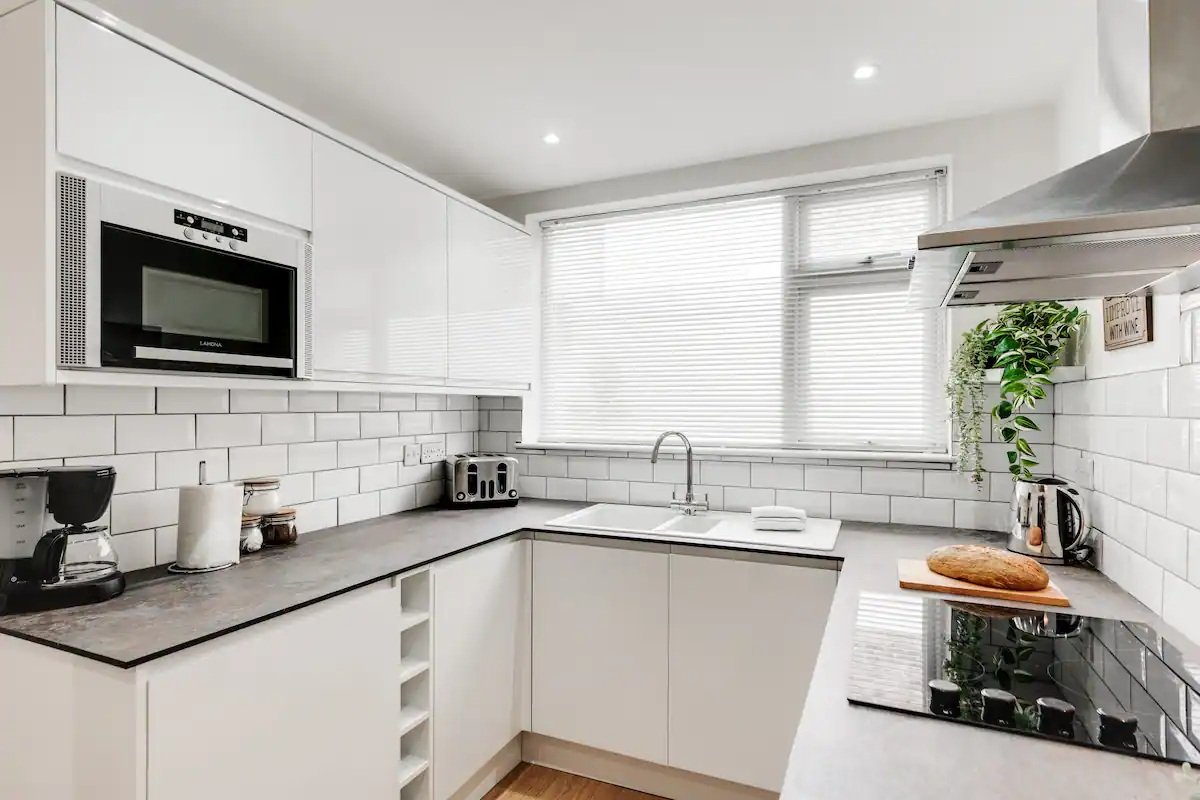 Modern white kitchen with subway tile backsplash, stainless steel appliances, and pendant lighting
