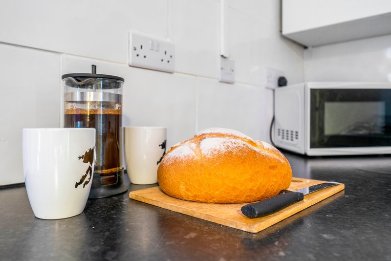 Modern kitchen counter with fresh bread, coffee carafe, mug and microwave