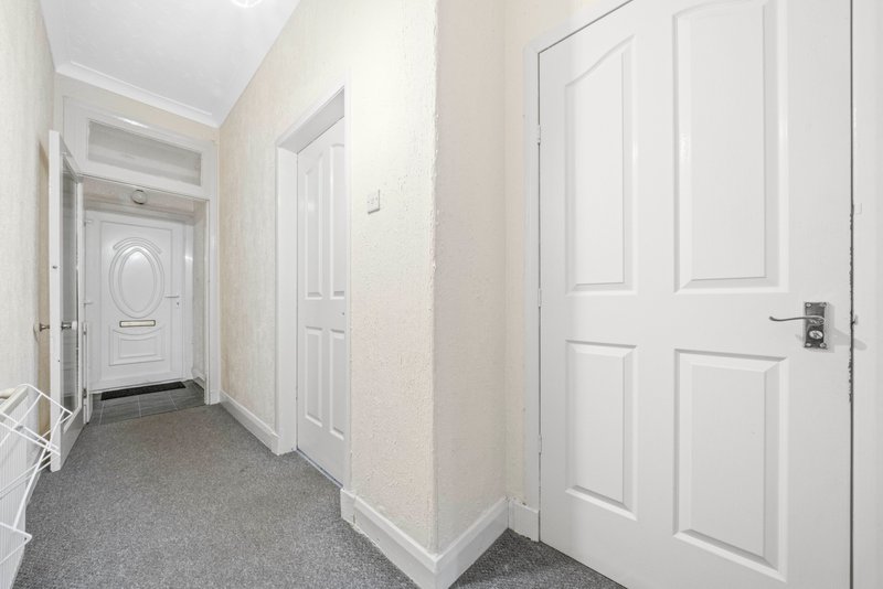 Clean hallway with white doors, gray carpet, and cream-colored walls