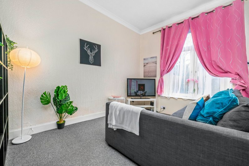 Modern bedroom with grey sofa, pink curtains, potted plant and floor lamp