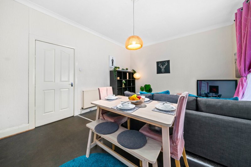 Open-plan living space with dining table, sofa, TV, and pendant lamp overhead