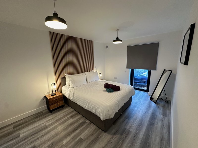 Modern bedroom with double bed, wooden nightstand, pendant lights and striped wall feature