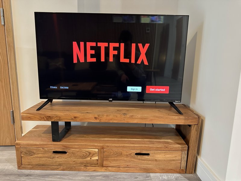 Wooden TV stand with drawers displaying Netflix app on flat-screen television