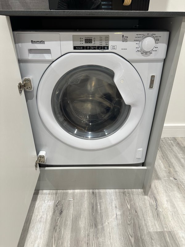 Built-in white washing machine with control panel in kitchen utility space