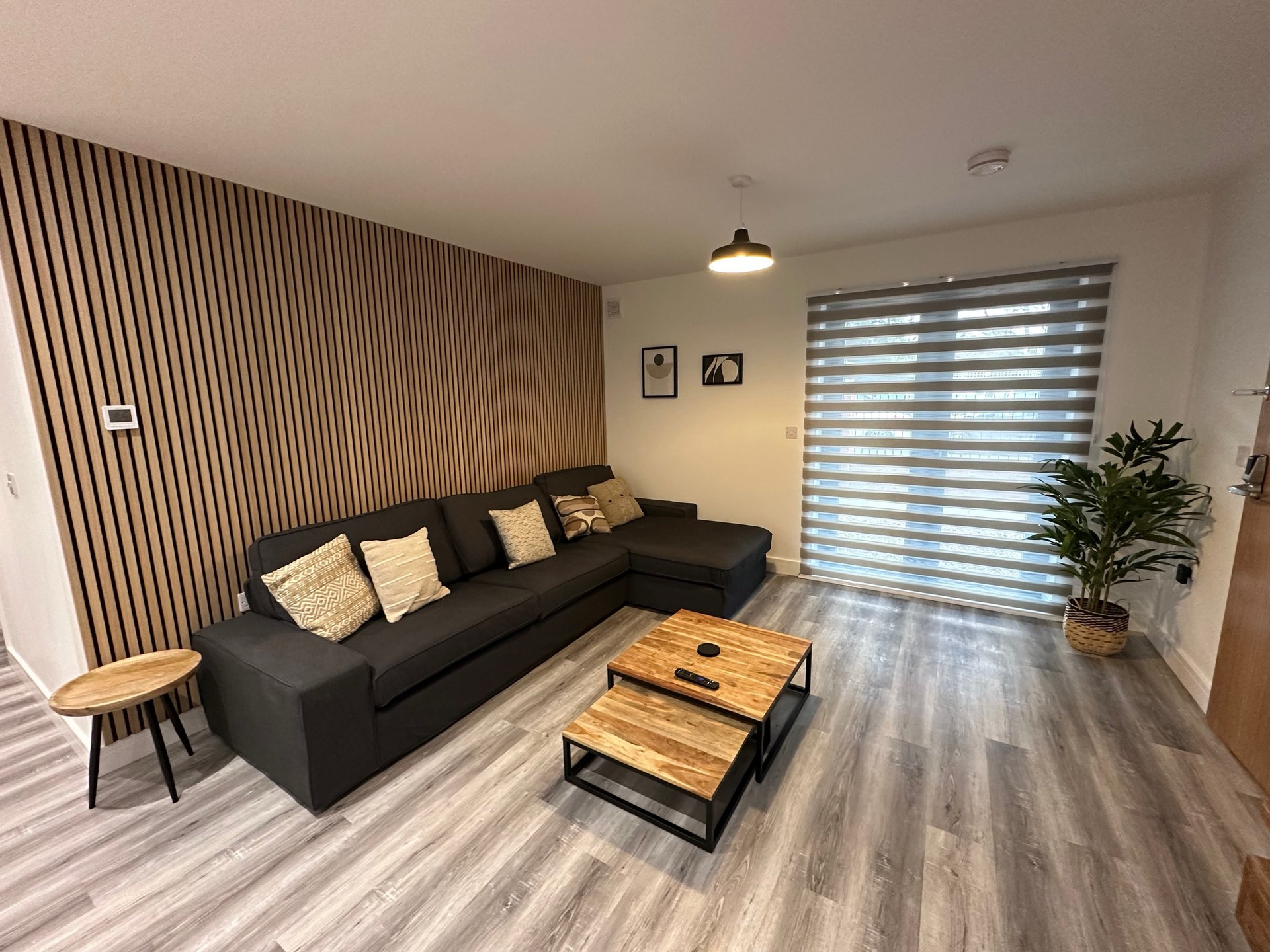 Modern living room with black sectional sofa, wooden coffee table and wall panelling